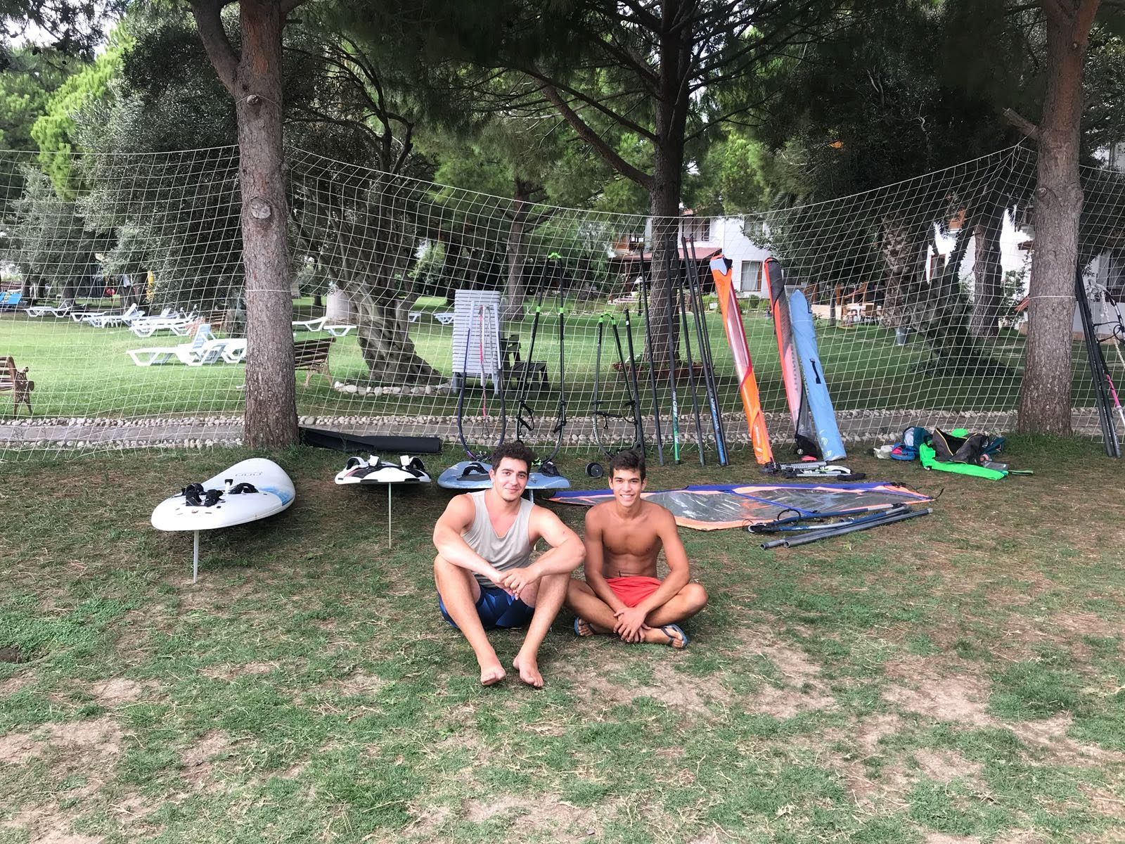 Two young windsurfing instructors seated in front of their teaching equipment in Güre, Balıkesir.